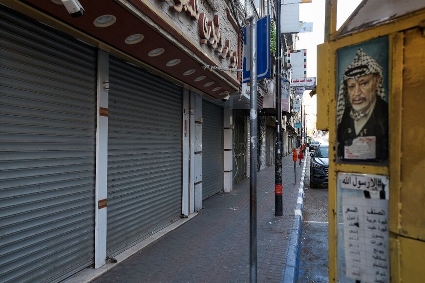 A portrait of the late Palestinian leader Yasser Arafat next to shuttered shops in the West bank city of Ramallah 