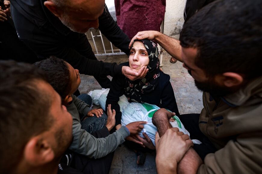 People try to comfort a woman holding the body of her baby girl killed in a strike on Rafah