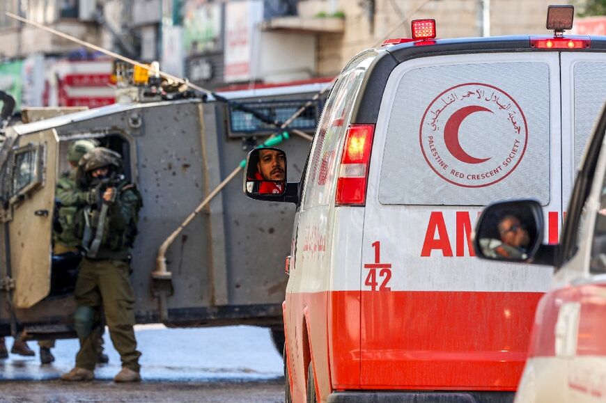 An Israeli soldier aims his weapon as Palestinian Red Crescent ambulances wait in Jenin