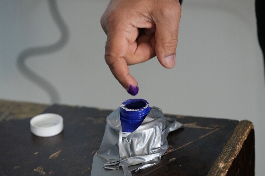 An Iraqi man stains his finger with ink after casting his ballot at a polling station in the central city of Najaf