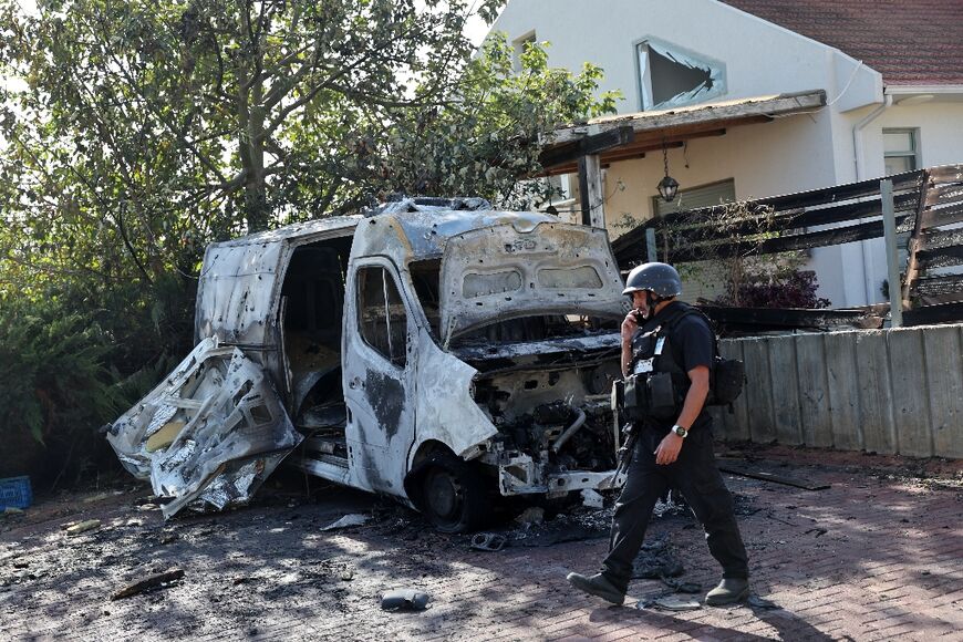 A member of Israel's security forces, in a community near the Gaza Strip, checks a destroyed vehicle hit by a rocket fired from Gaza after fighting resumed