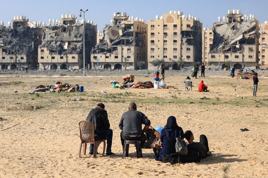 Residents of the Qatari-funded Hamad City residential complex in the Gaza Strip sit outside after  Israeli air strikes hit the development