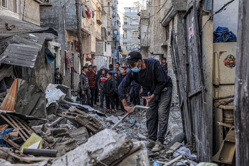 People inspect the rubble of a building destroyed by Israeli bombardment in Rafah in the southern Gaza Strip on December 24, 2023 