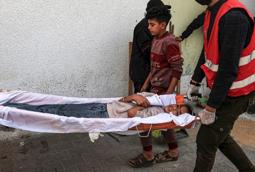 Paramedics in Rafah carry into a hospital a child injured during Israeli bombardment 