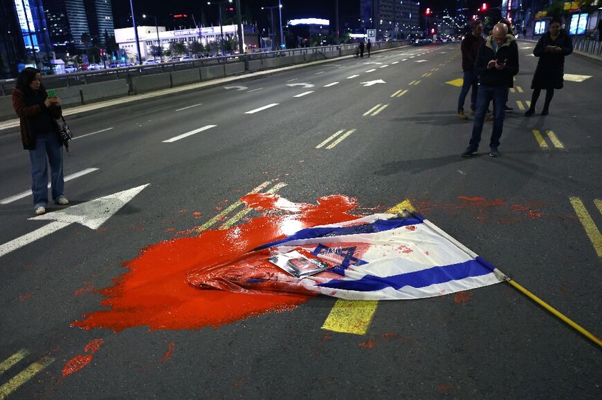 An Israeli flag is covered in red paint at the Tel Aviv demonstration over hostages