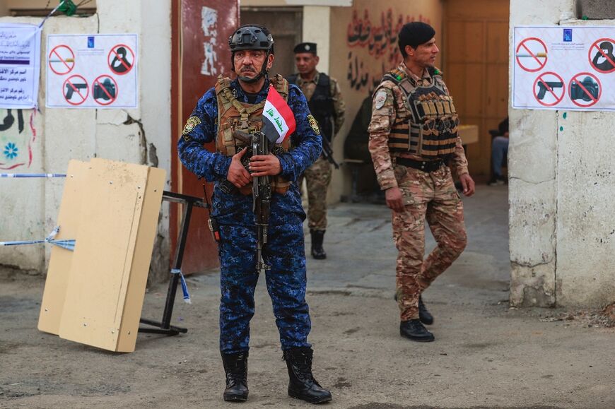 Security force personnel stand guard  outside a polling station in the Sadr City district of Baghdad