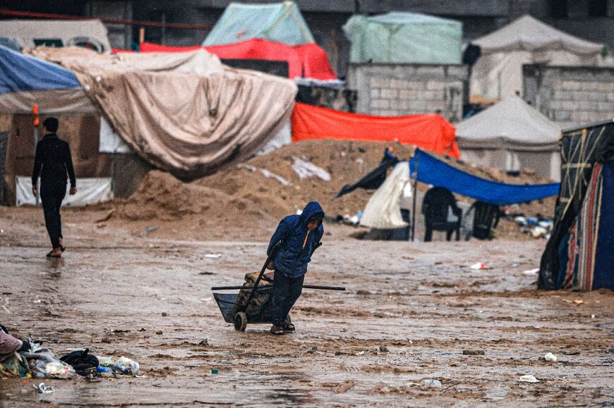 A Palestinian drags brickes at a camp for displaced people in Rafah, in the southern Gaza Strip where most civilians have taken refuge, on December 13, 2023