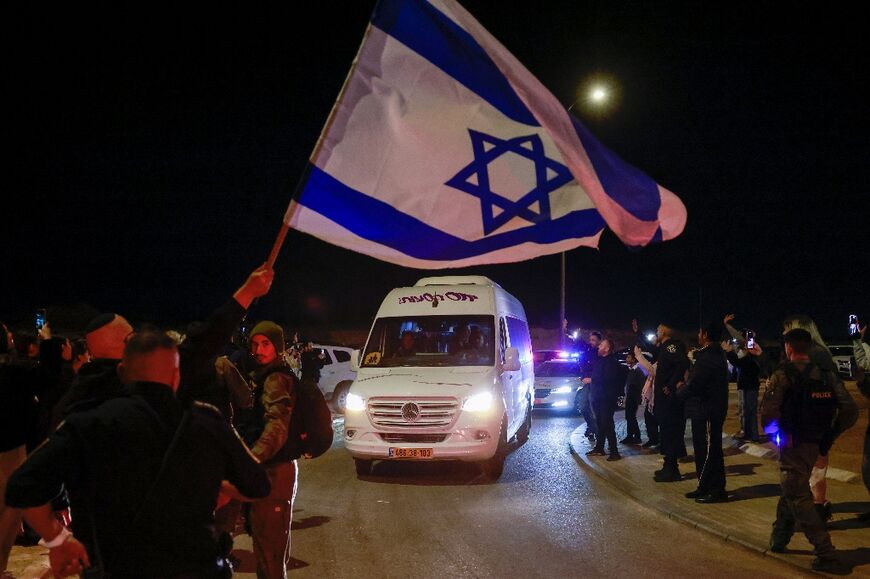 Supporters wave the Israeli flag as they wait for newly released hostages