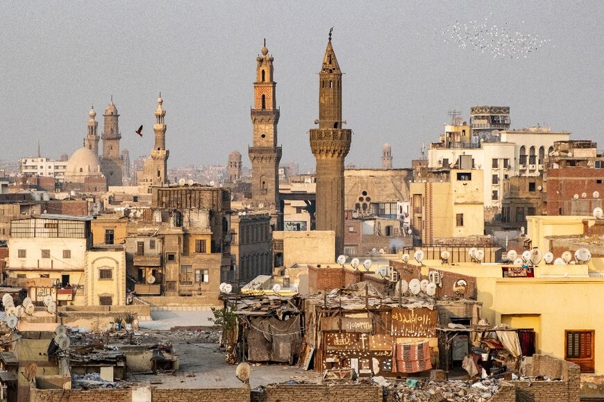 A flock of birds flies over the buildings and mosque minarets within the old city walls of Cairo 