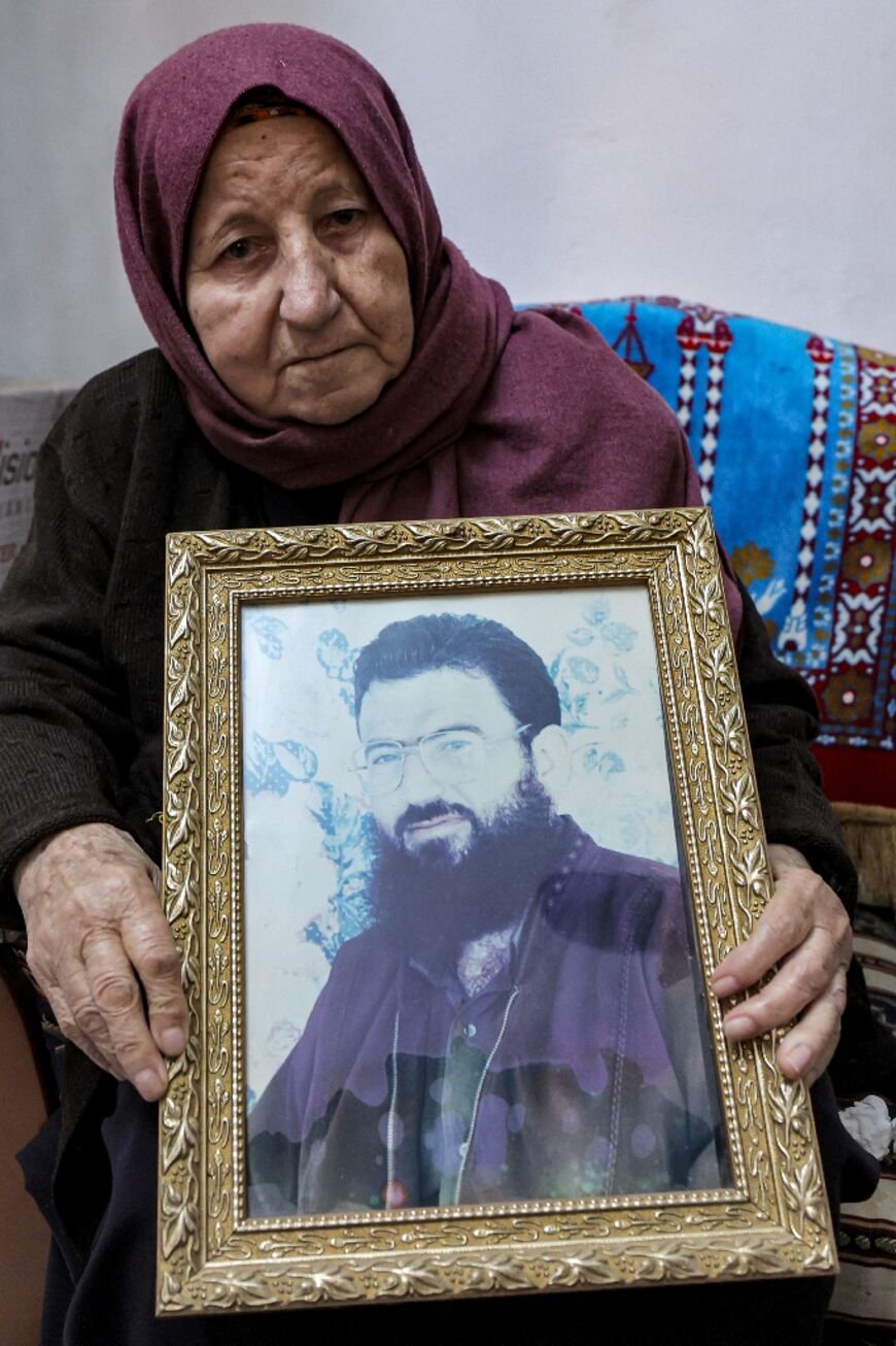 Aisha, mother of Saleh al-Aruri, sits holding a picture of him at their family house in the town Arura, north of Ramallah in the occupied West Bank, on January 3, 2024