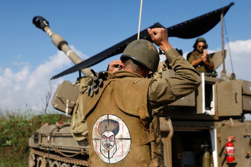 A soldier manning a howitzer shelling Lebanon from northern Israel wears a patch on the back of his flak jacket showing Hezbollah leader Hassan Nasrallah in his sights