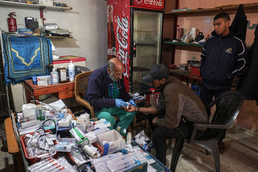Zaki Shaheen, a retired nurse who turned his shop in Rafah into a clinic to help displaced Gazans, treats a wounded man