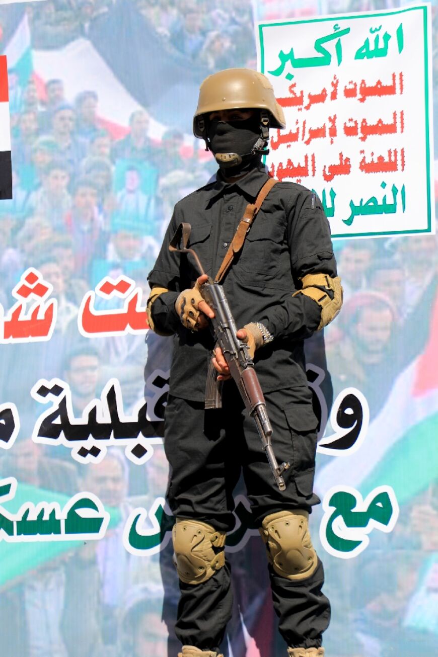 A Huthi fighter in front of a banner which reads in Arabic: "Death to America, Death to Israel" on January 11, 2024 