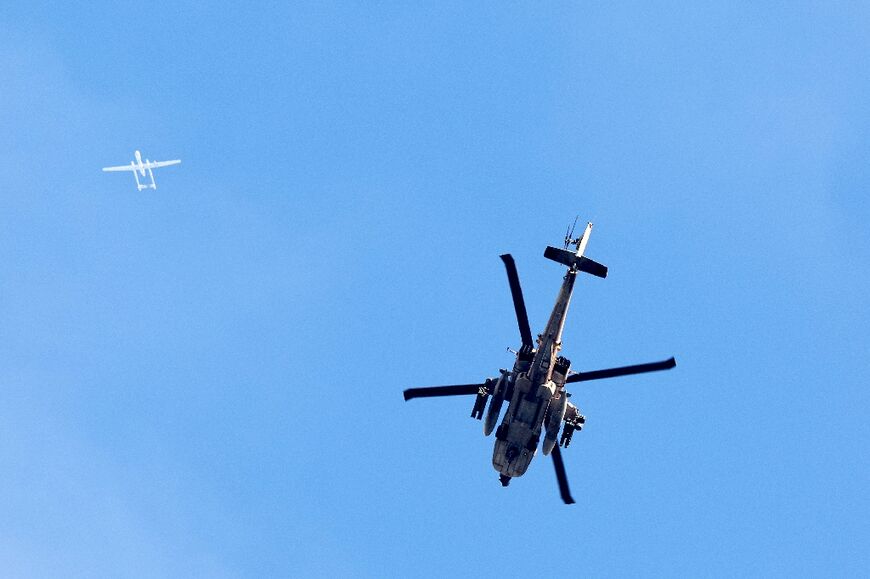 An Israeli Air Force attack helicopter (R) and drone (L)  fly over the northern Gaza Strip near the border with southern Israel