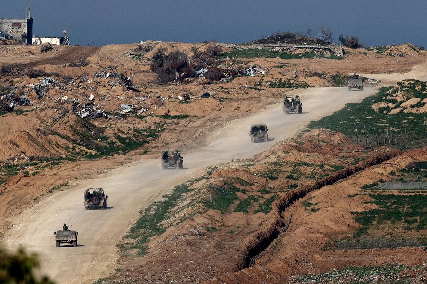Israeli army vehicles drive on a road in Gaza, seen from southern Israel