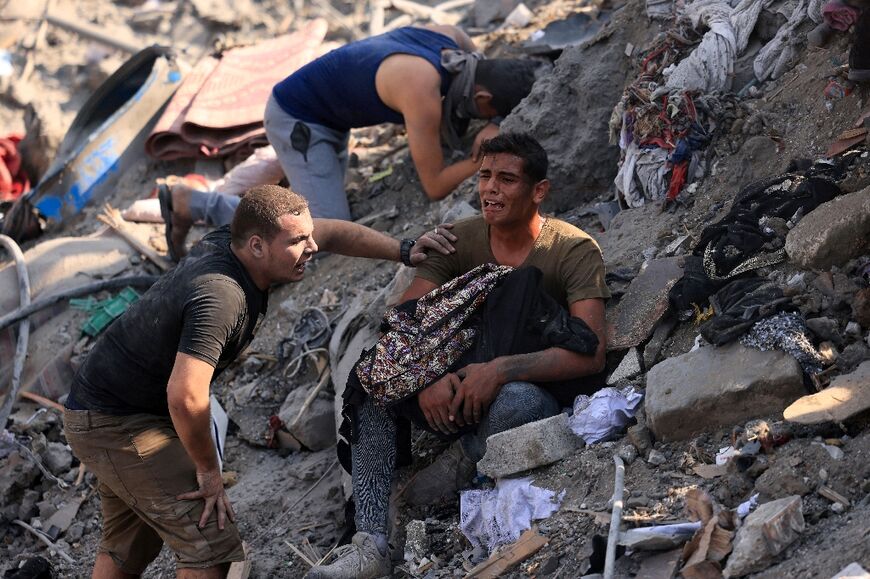 A man reacts as he holds the remains of his mother wrapped in a blanket among the rubble of a building destroyed in an Israeli strike on Gaza's Bureij refugee camp, on November 2, 2023