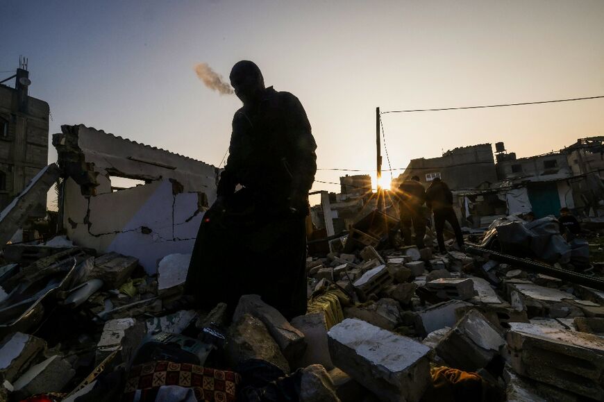 A man smokes a cigarette amid the rubble of a building destroyed by Israeli bombardment in the Rafah refugee camp