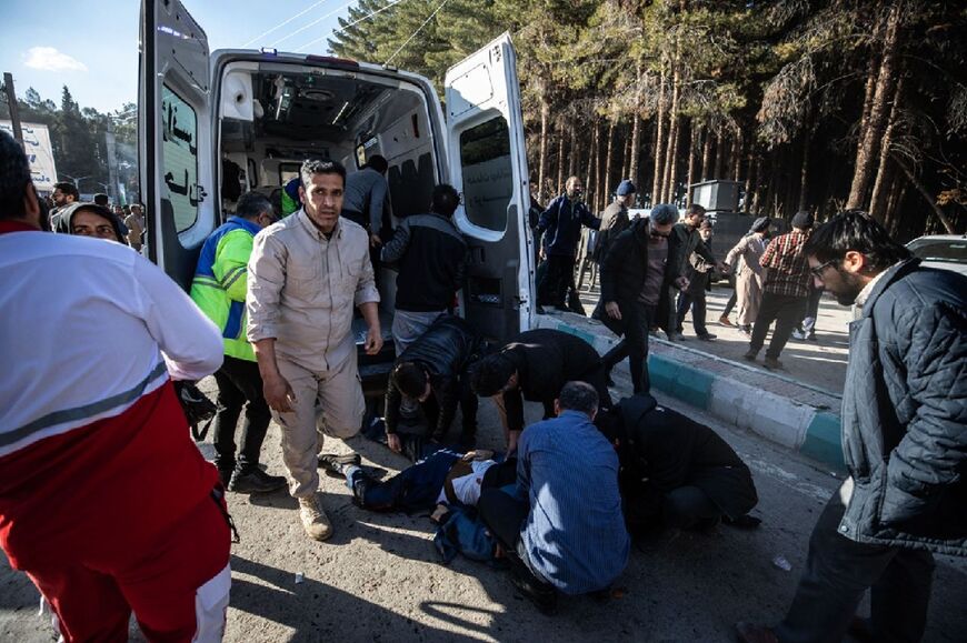 Iranian emergency services assist a person at the site of the explosions in southern Iran that killed dozens