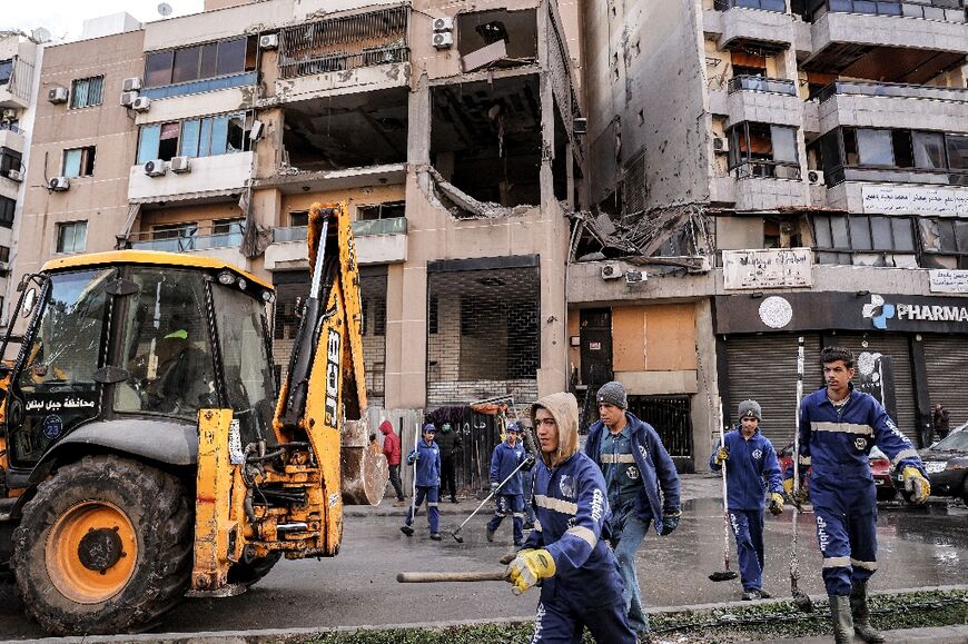 Municipal workers in Beirut clean the street in front of the building hit by a strike that killed Hamas deputy leader Saleh al-Aruri 