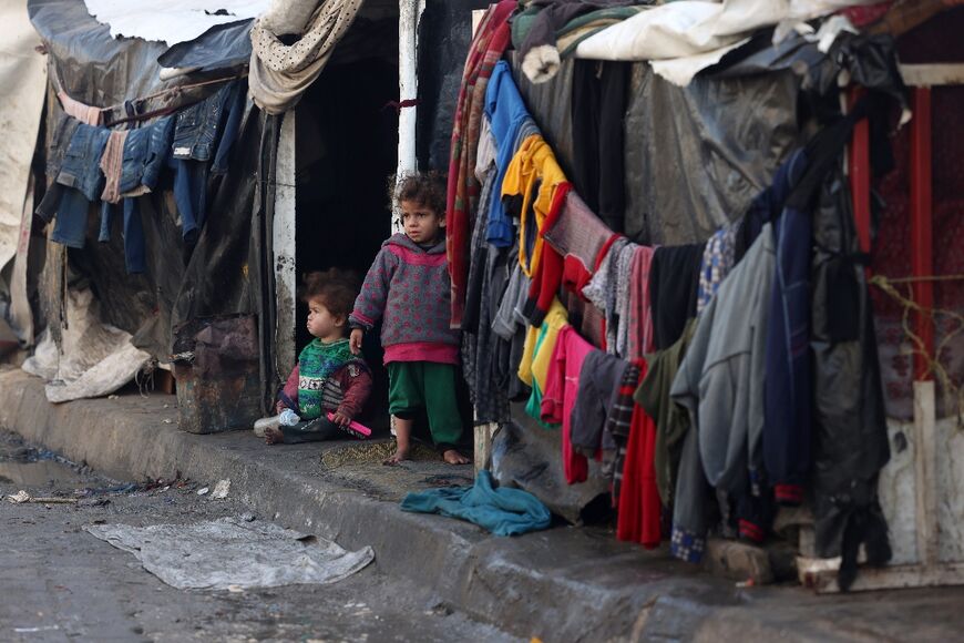 Children stand outside tents at a makeshift tent camp housing displaced Palestinians in Rafah