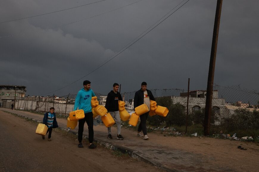 Displaced Palestinians carry jerricans on their way to get water in Rafah