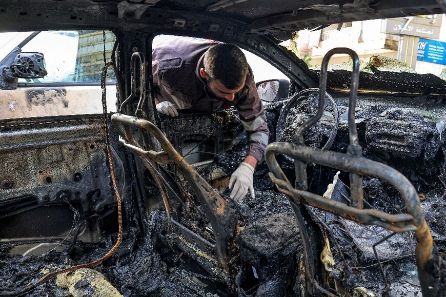 Civil defence workers inspect a vehicle that was damaged near the building where Saleh al-Aruri was killed