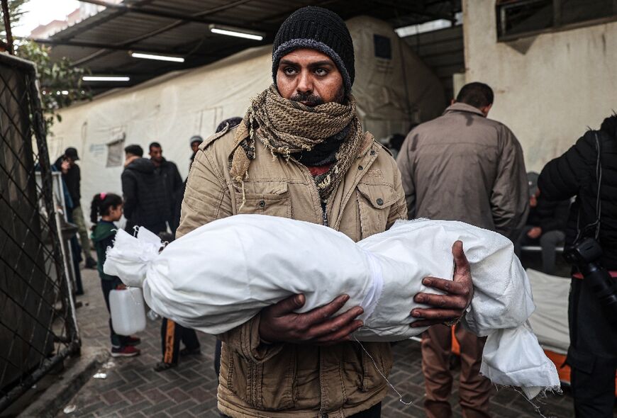 A Palestinian man carries the body of a child killed in the latest bombardment of Rafah