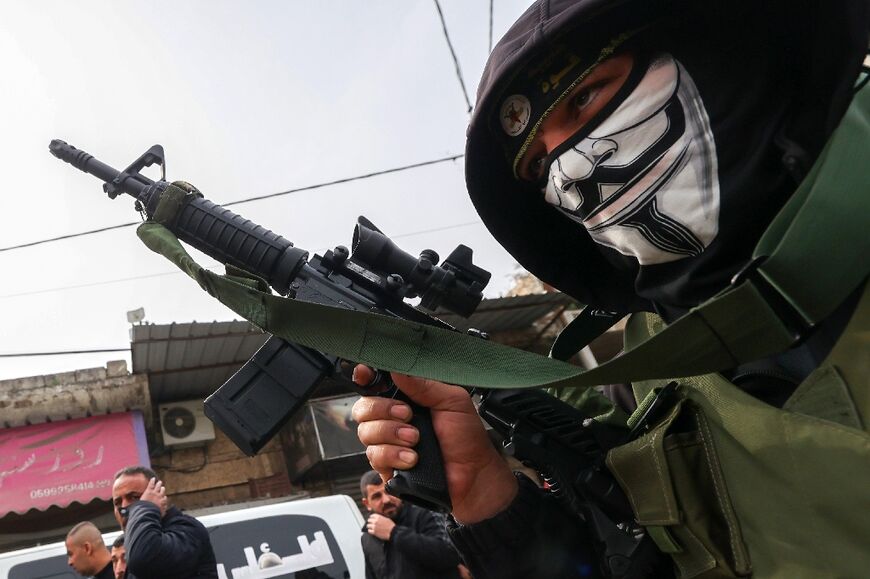A masked gunman from the Al-Quds brigades, the armed wing of the Islamic Jihad movement, takes part in the funeral procession of two Palestinian men killed in an overnight Israeli strike on Jenin in the occupied West Bank, on February 23, 2024