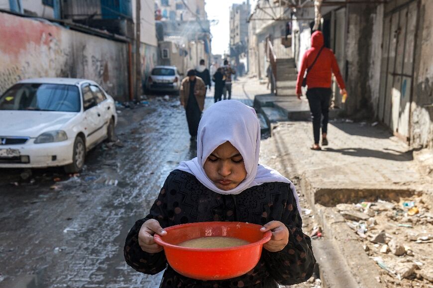 A girl carries a bowl of lentil soup in the southern Gaza city of Rafah 