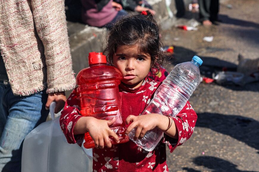 A girl carries plastic bottles filled with water in Rafah in the southern Gaza Strip on February 8, 2024