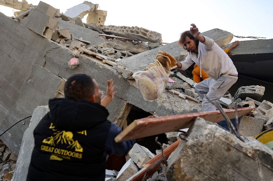 Palestinian men salvage bread found amid the rubble of the Abu Anza family home in Rafah