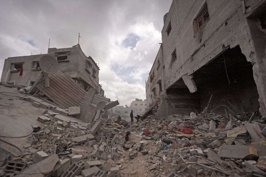 Palestinians walk amid the rubble of houses destroyed by Israeli bombardment in Khan Yunis in the southern Gaza Strip