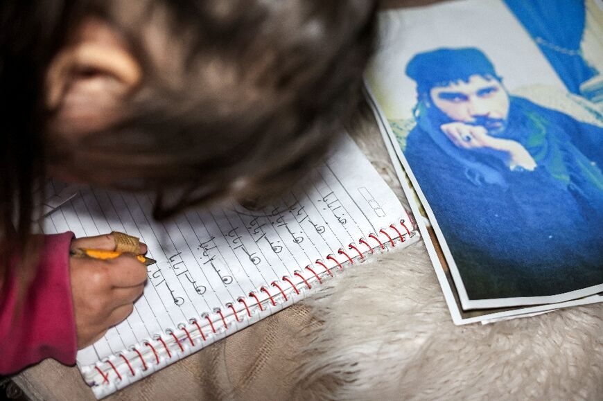 Syrian detainee Ahmed Majluba's daughter practices writing 'this is dad' alongside a picture of him