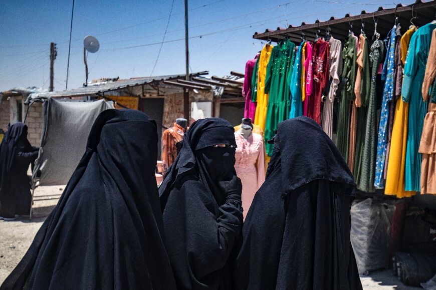 Women walk past a dress shop in the Iraqi and Syrian sector of the al-Hol camp 