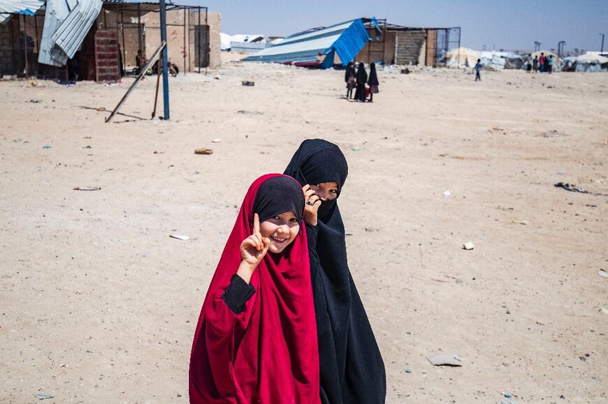 Two girls point to the sky -- a gesture often used by Islamic State -- in the al-Hol camp in Syria where the families of IS fighters are held