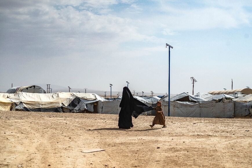 A girl walks behind her mother through the vast al-Hol camp in northeastern Syria