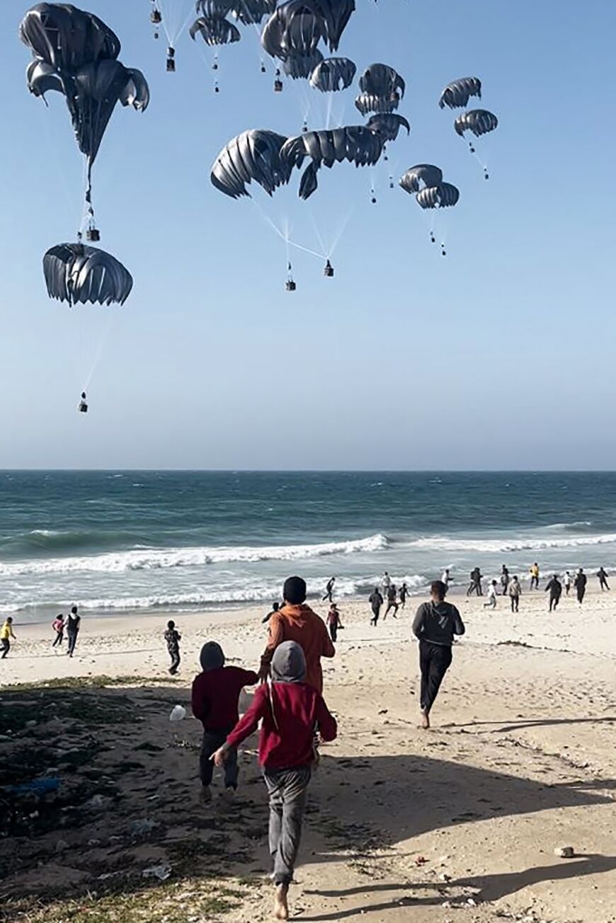 Palestinians running toward parachutes attached to food parcels, airdropped from US aircrafts on a beach in the Gaza Strip