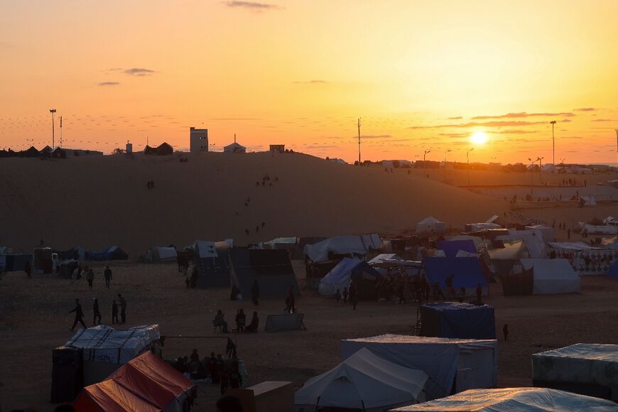 The sun sets behind a camp for displaced Palestinians in Rafah, in the southern Gaza Strip, on the eve of Ramadan