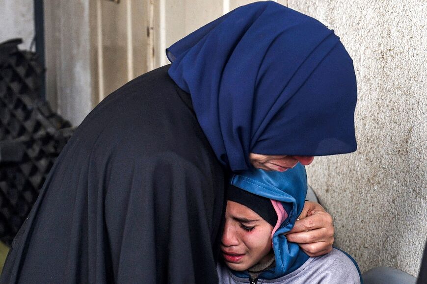 A woman embraces a crying child as they mourn relatives who were killed during overnight Israeli bombardment, at al-Najar Hospital in Rafah in the southern Gaza Strip