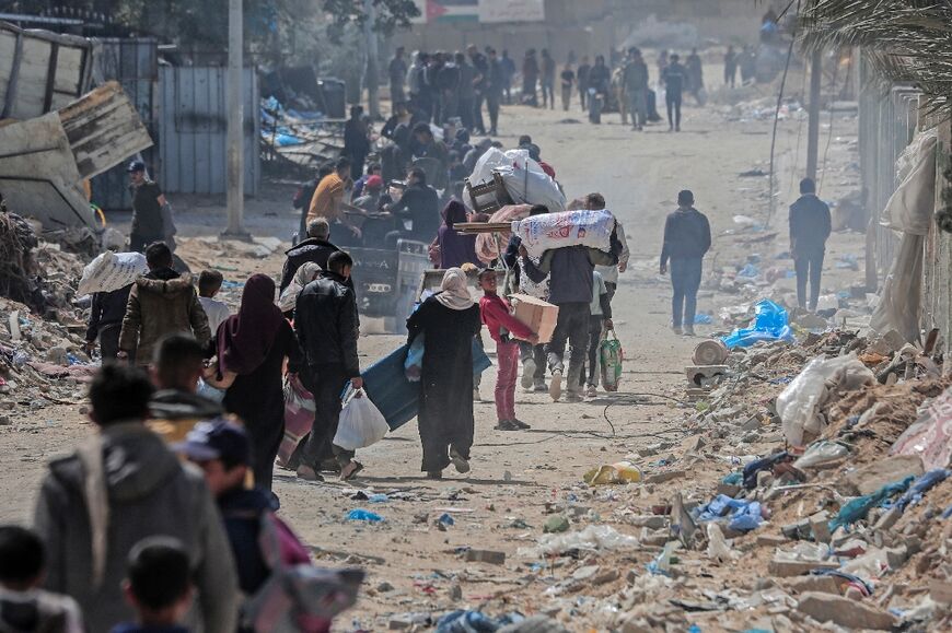 Displaced Palestinians carry their belongings through a street in the southern Gaza city of Khan Yunis