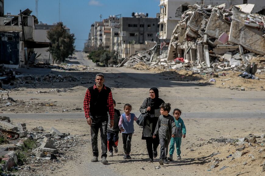 A Palestinian family walks through the destruction of Gaza City, in the territory's north where aid workers say the humanitarian situation is particularly actue