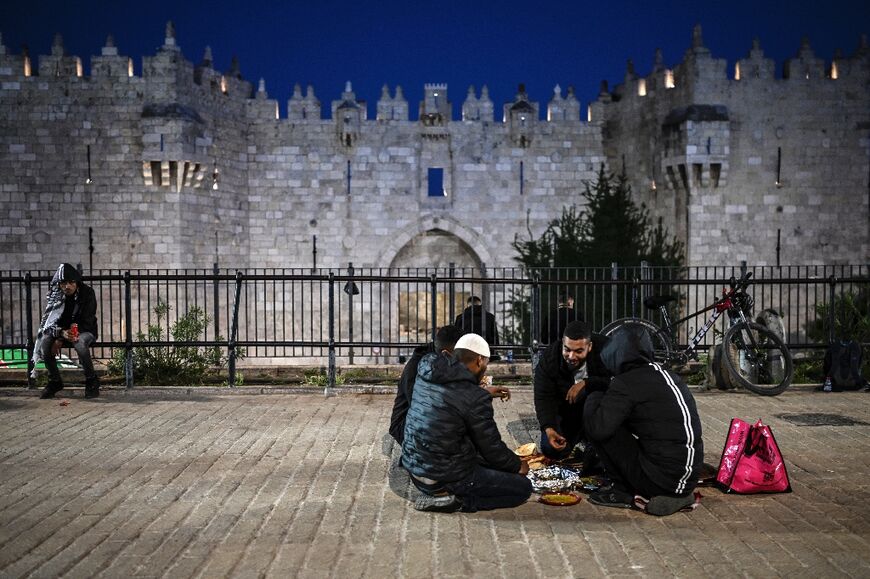 Palestinian Muslims break their day-long Ramadan fast together during an "Iftar" meal organised by a charity outside the Damascus Gate of the Old City of Jerusalem on April 5, 2024