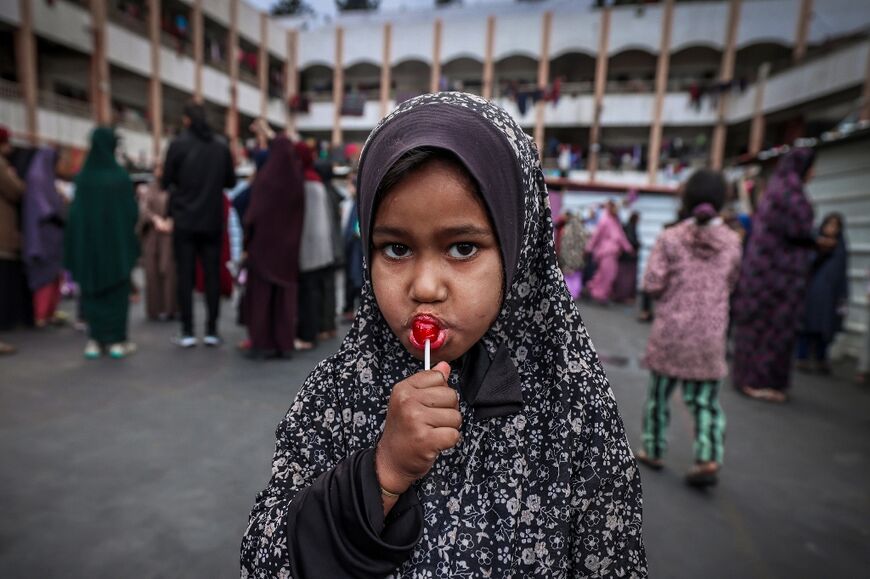 A displaced child licks a lollipop after a special morning prayer to start the Eid al-Fitr festival, marking the end of the holy month of Ramadan, at a camp in a repurposed school in Rafah, southern Gaza