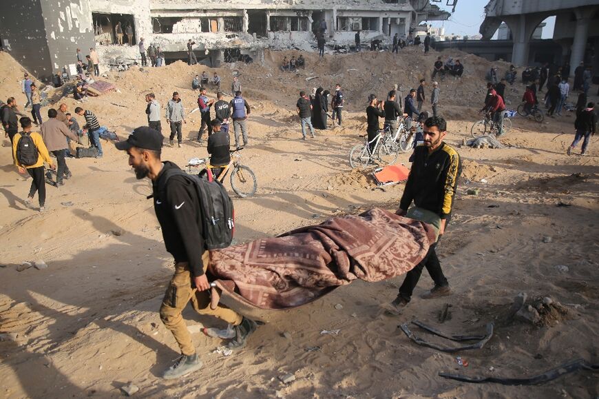 Palestinians carry away a covered body as people gather to inspect the damage at Gaza's Al-Shifa hospital