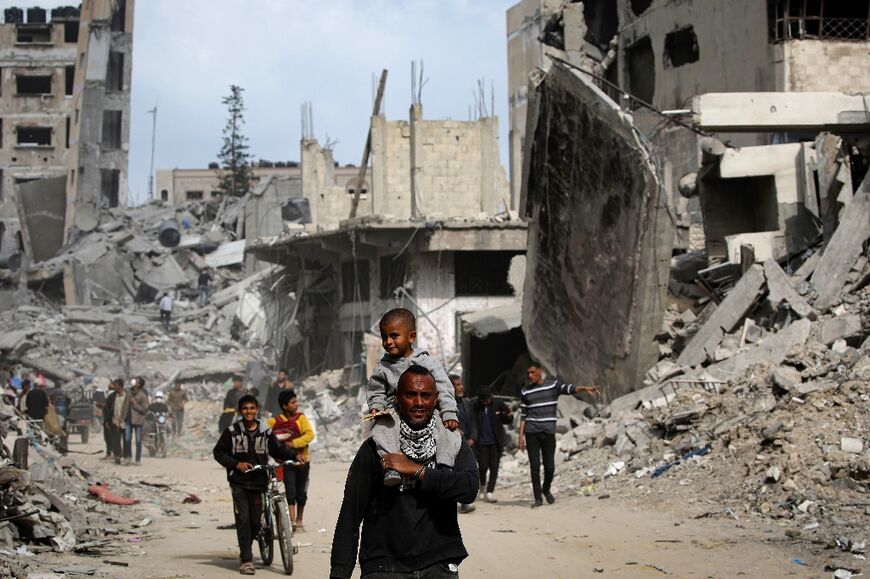 A Gazan man carried a child through the rubble of Khan Yunis
