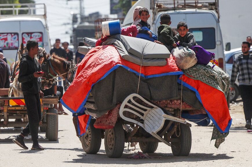 Palestinian children sit on top of their family's belongings as they flee fighting in Nuseirat in central Gaza on a horse-drawn cart.