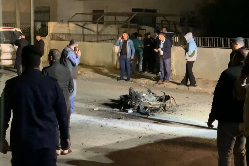 An image grab from AFPTV footage shows Jordanian onlookers and security agents standing around the debris of a missile that the Jordanian forces intercepted over Amman in the early hours of April 14, 2024