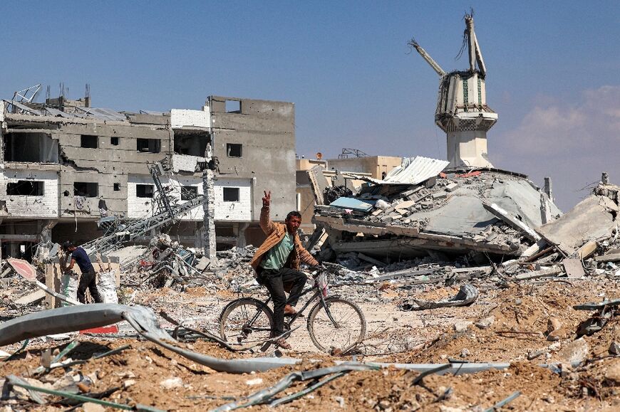A man rides a bicycle past destroyed buildings in Khan Yunis on April 7, 2024 