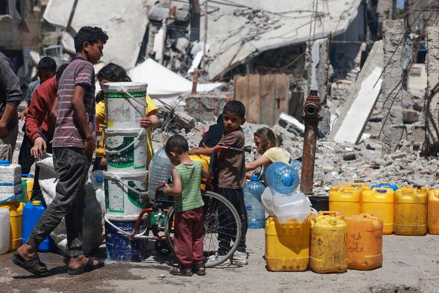 Displaced Palestinians line up to fill their containers with water in Rafah, in the southern Gaza Strip on April 19, 2024