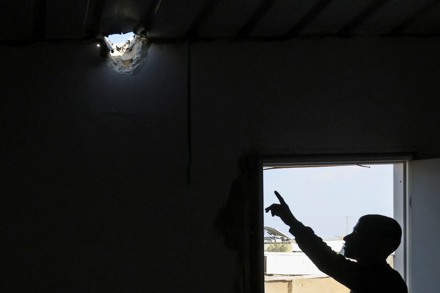 A relative points to a hole in the roof of a building caused by a projectile that injured seven-year-old Bedouin girl Amina in her village in the southern Negev desert on April 14, 2024